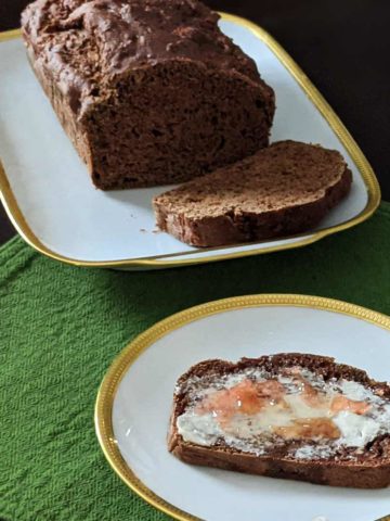 Photo of a loaf of apple ginger quick bread and a slice with vegan butter and marmalade.