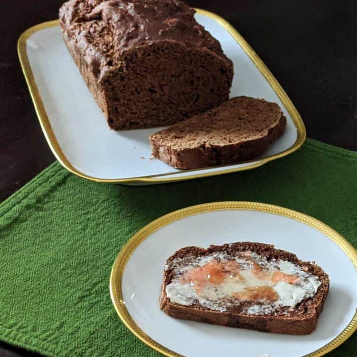 Photo of a loaf of apple ginger quick bread and a slice with vegan butter and marmalade.