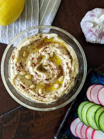 Overhead photo of a bowl of homemade hummus with sliced vegetables