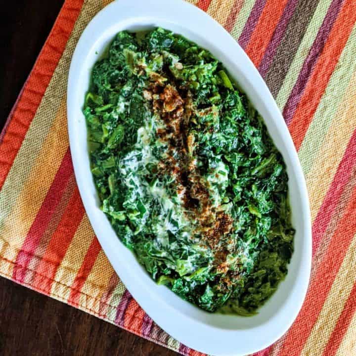 Photo of a dish of vegan creamed spinach on a colorful cloth