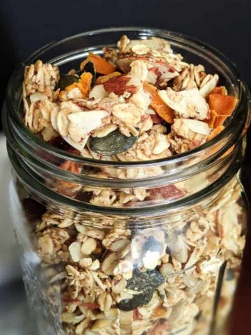 Close up photo of a jar of homemade granola with mangoes and almonds