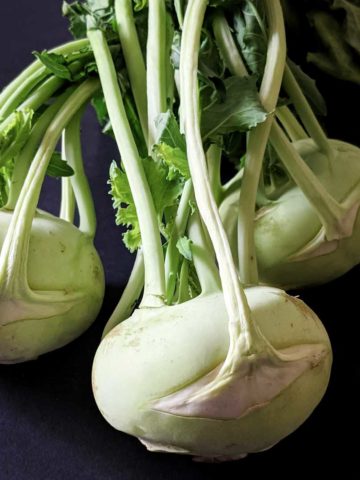 Photo of three kohlrabi bulbs with their greens