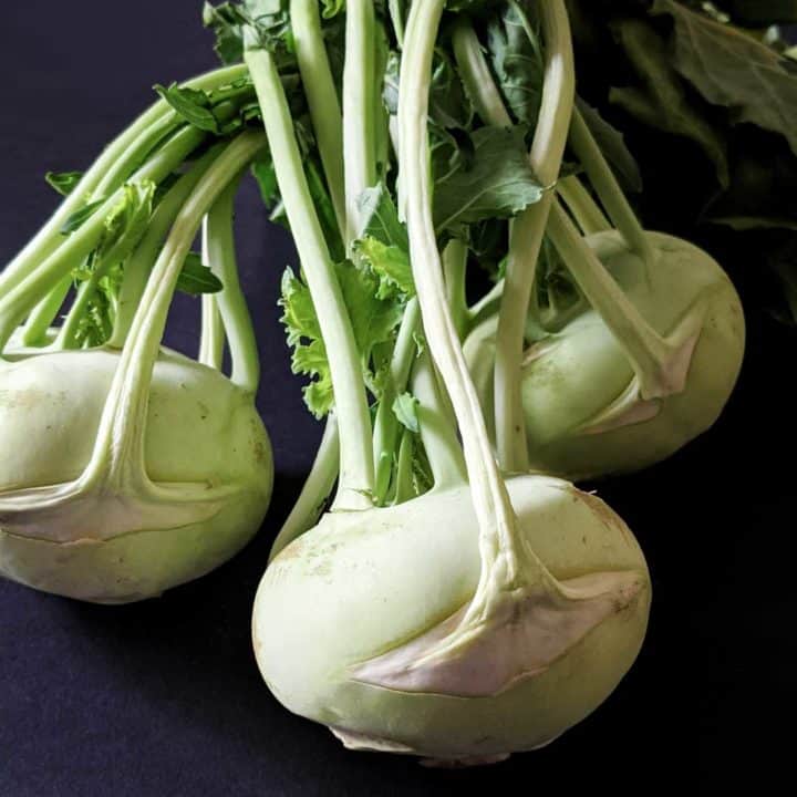 Photo of three kohlrabi bulbs with their greens