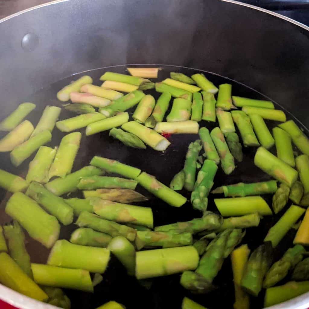 Overhead photo of chopped asparagus in a pot of boiling water