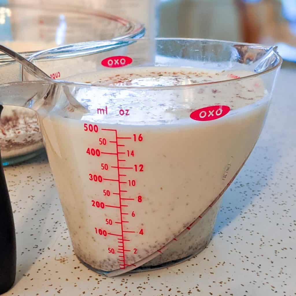 Photo of a large measuring cup filled with oat milk and flaxseed meal