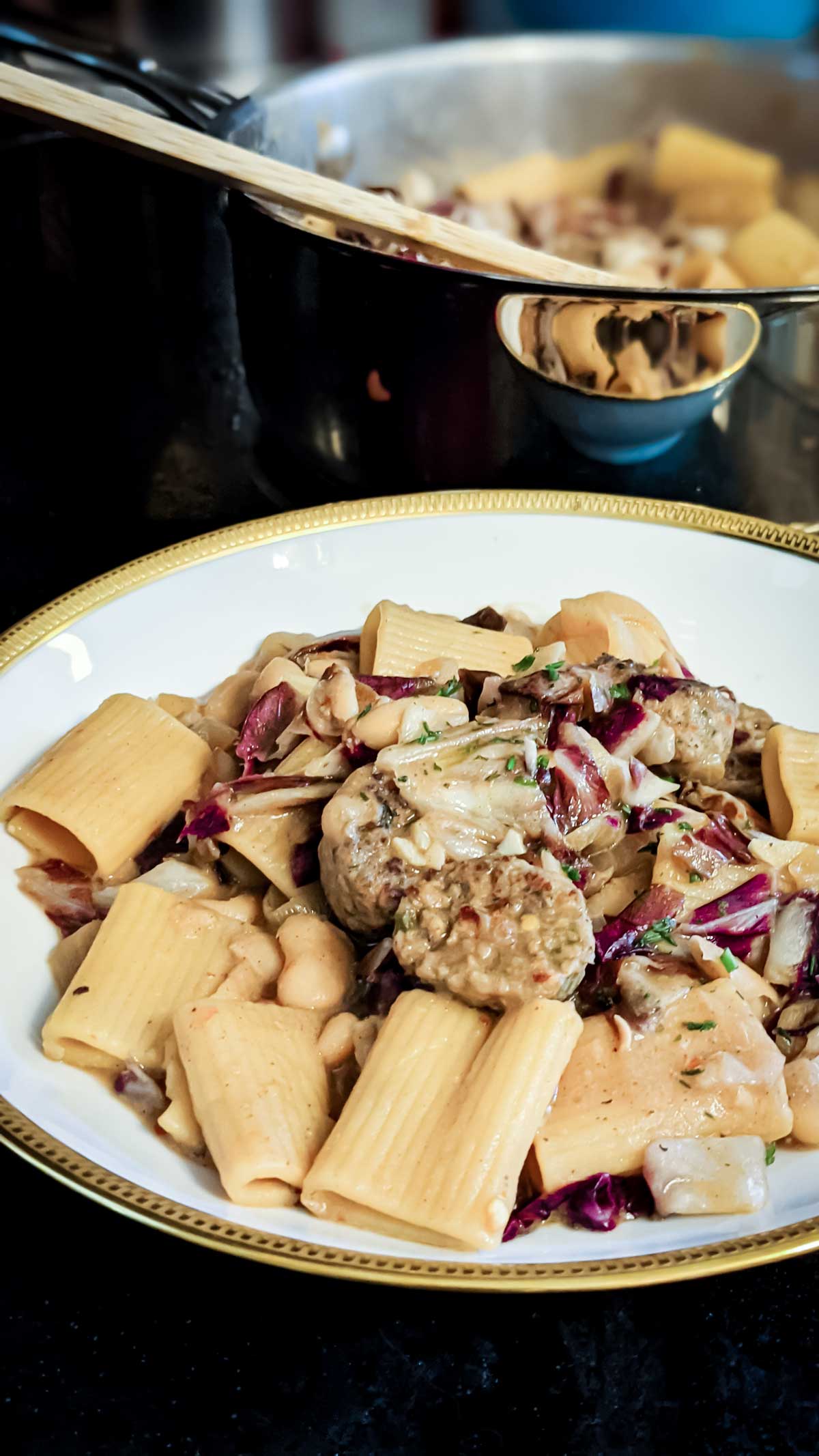 Photo of a pan and bowl filled with pasta with vegan sausage, radicchio, and white bean pasta