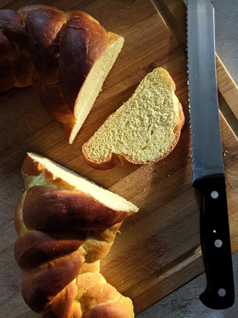 photo of sliced challah with bread knife on a cutting board