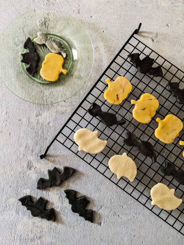 Overhead photo of halloween marzipan in orange, black, and white, formed into the shapes of bats, cats, pumpkins, and ghosts