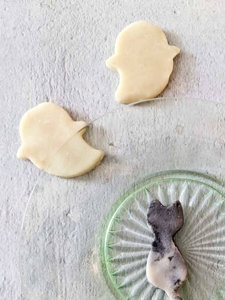 Photo of two marzipan ghosts next to a plate with a marzipan cat