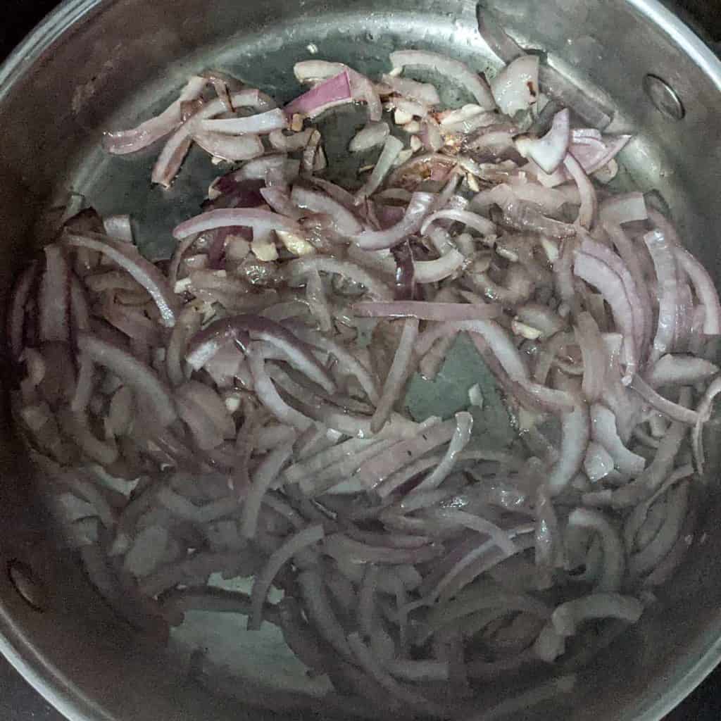 Overhead photo of a large pot with translucent sliced onions and garlic