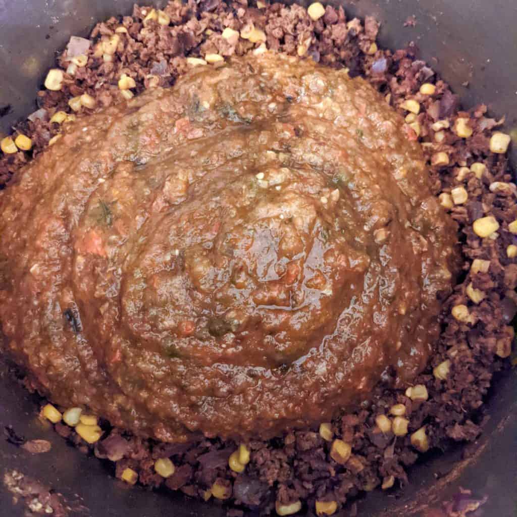 Photo of vegetable mixture being added to pot of chili