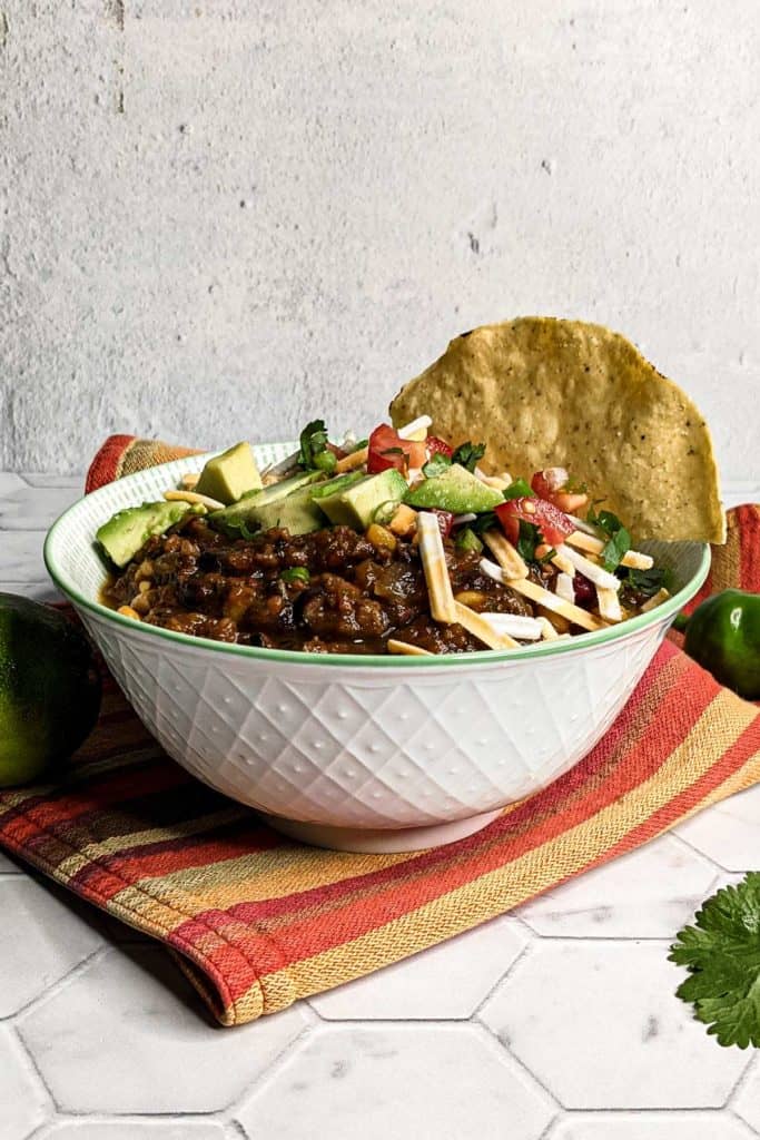 Side-view photo of a bowl of vegan chili on a colorful cloth