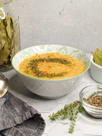 Photo of a bowl of split pea soup with a spoon, cloth napkin and garnishes
