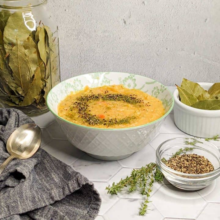 Photo of a bowl of split pea soup with a spoon, cloth napkin and garnishes