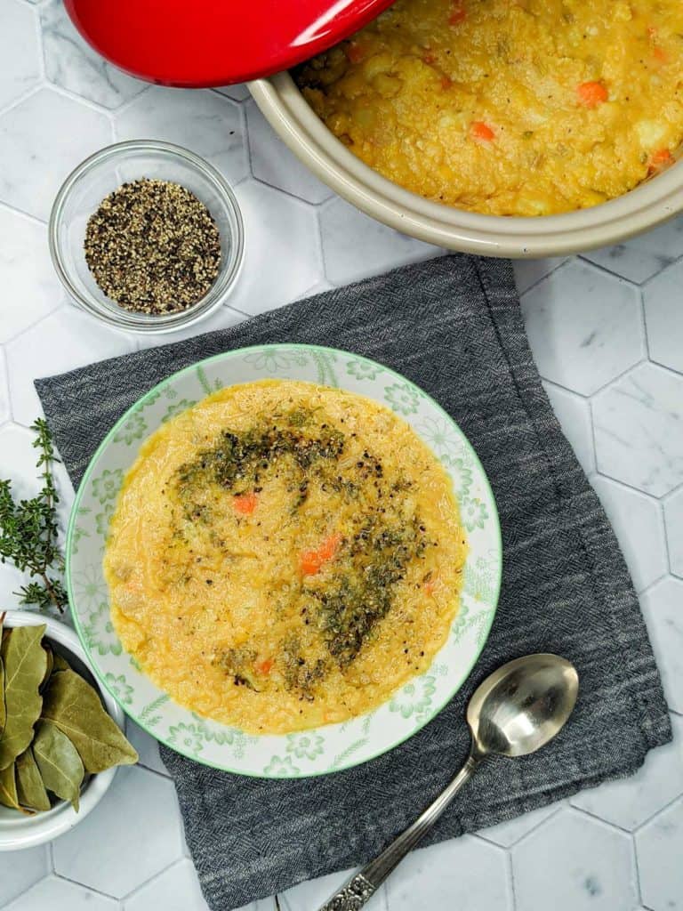 Photo of a bowl of split pea soup with a spoon, cloth napkin and garnishes