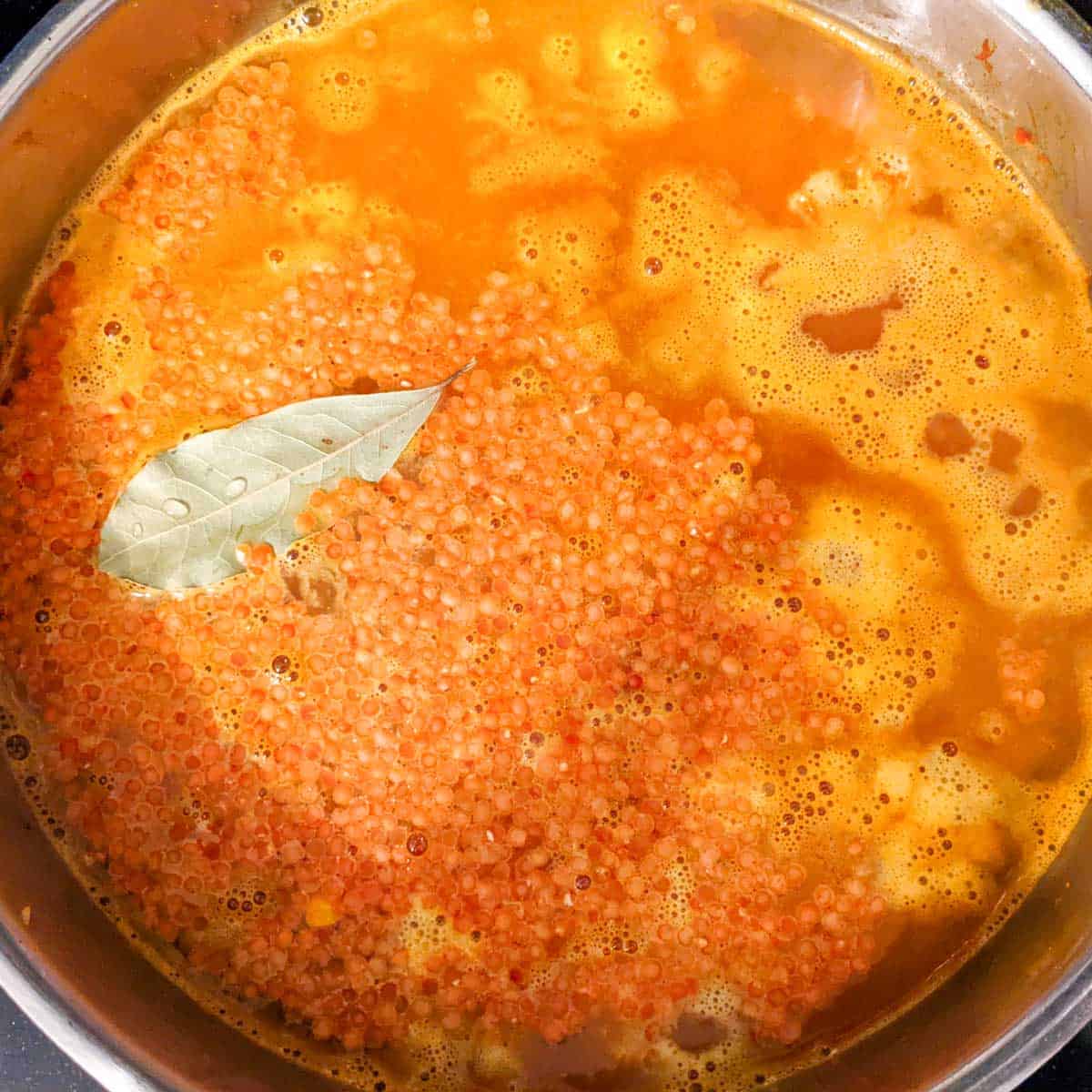 Photo of red lentils with broth and bay leaf