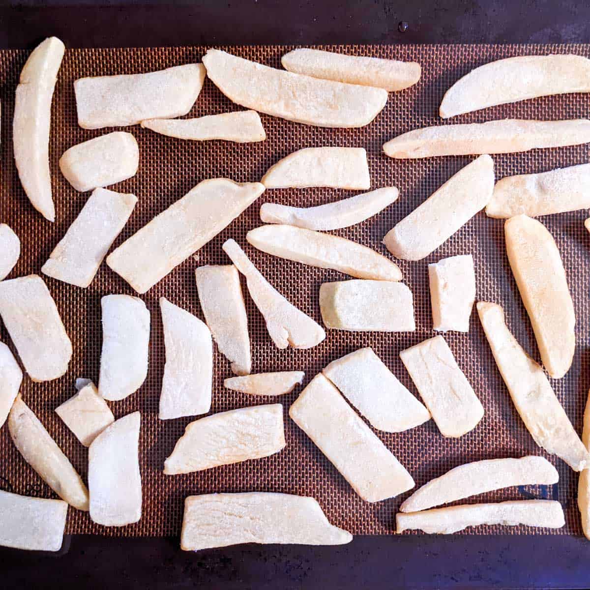 Overhead photo of a baking sheet with frozen french fries, ready to bake in the oven